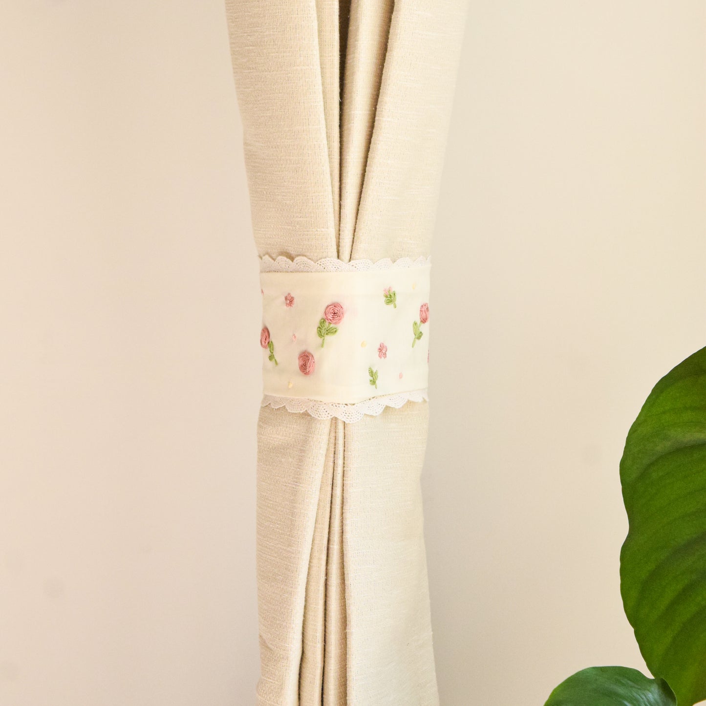Beige curtain with floral embroidery on a plain background