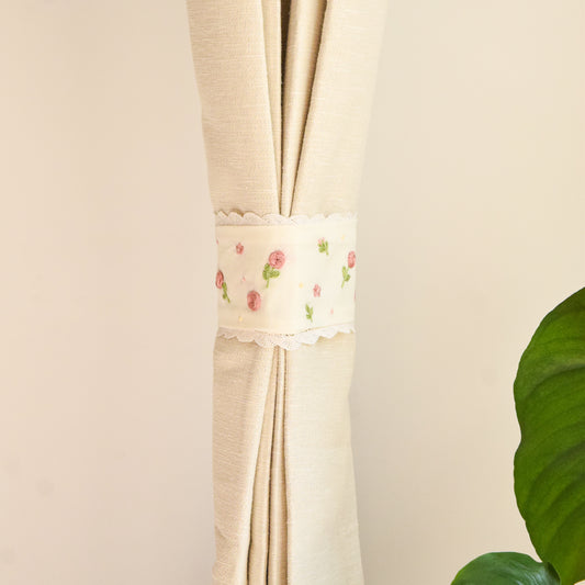 Beige curtain with floral embroidery on a plain background