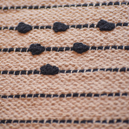 Close-up of woven fabric with black thread pattern on beige background