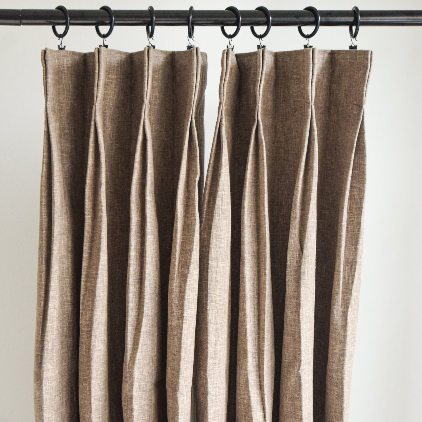 Brown striped curtain hanging on a rod against a white background