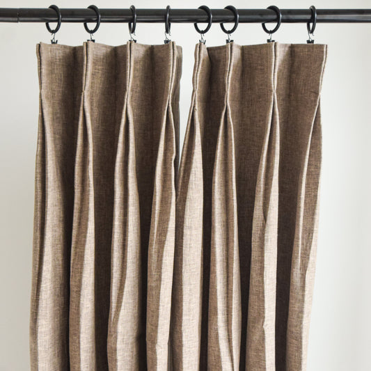 Brown striped curtain hanging on a rod against a white background