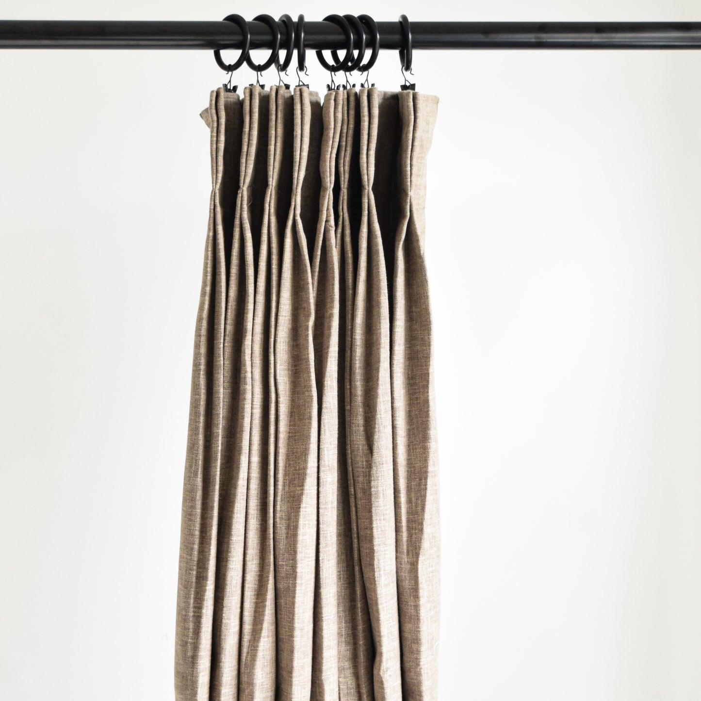 Beige curtains hanging on a rod against a white background