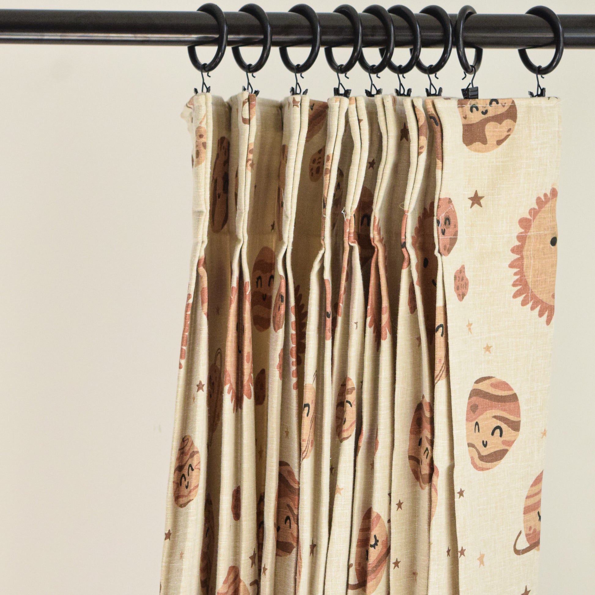 Curtain with animal pattern hanging on a rod against a plain background