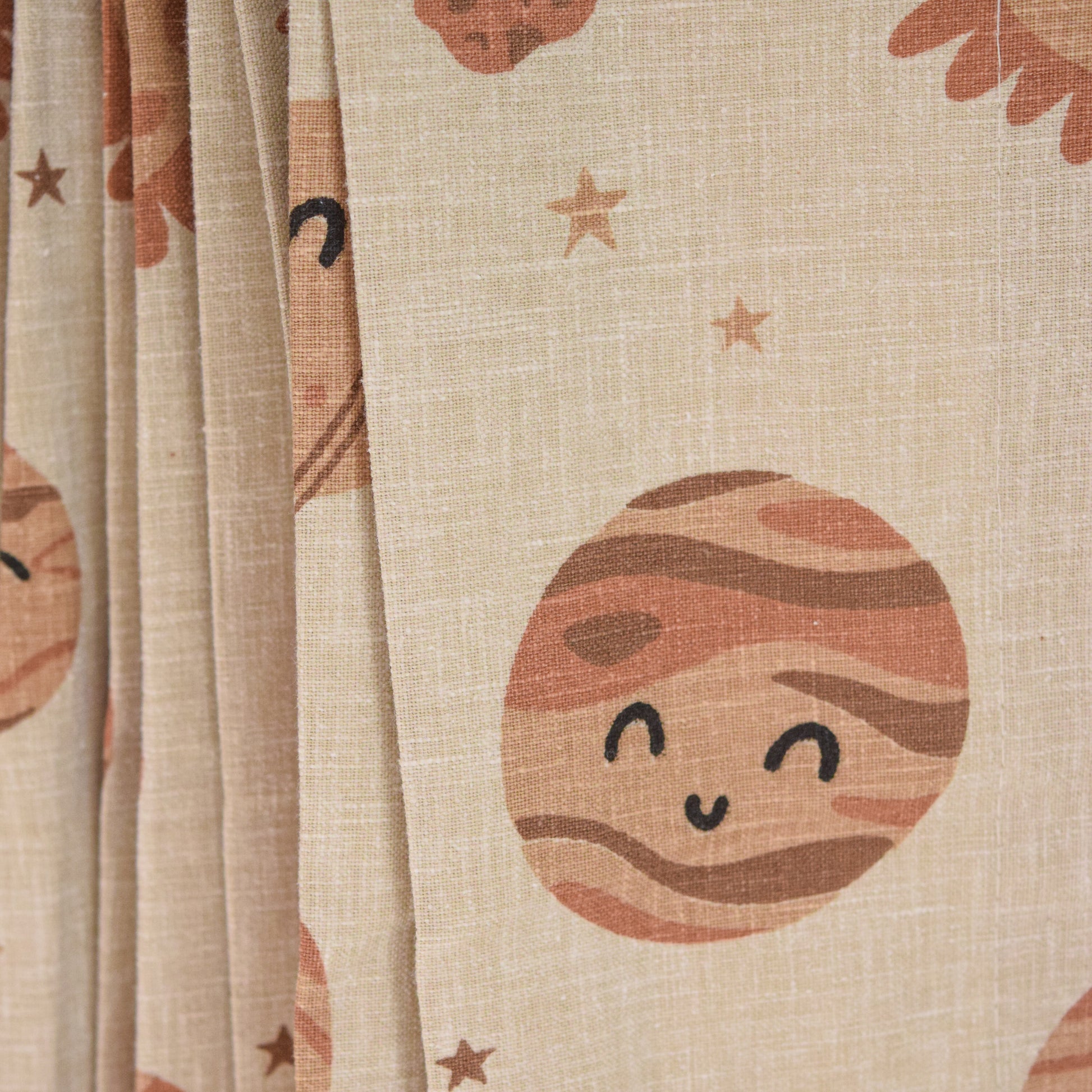 Textile with cartoon planet and star designs on a beige background