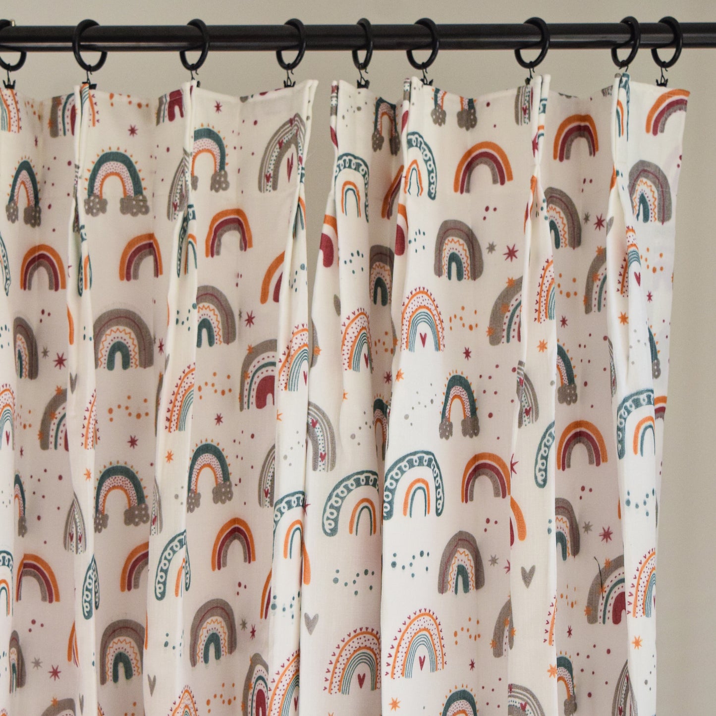 Curtains with rainbow pattern hanging on a rod against a neutral background