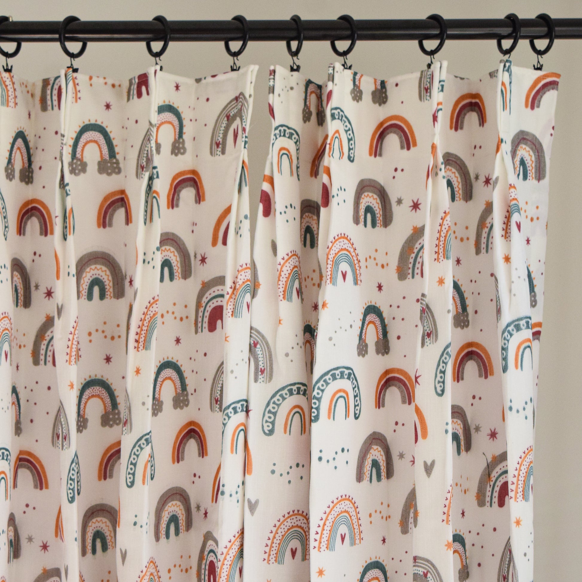 Curtains with rainbow pattern hanging on a rod against a neutral background