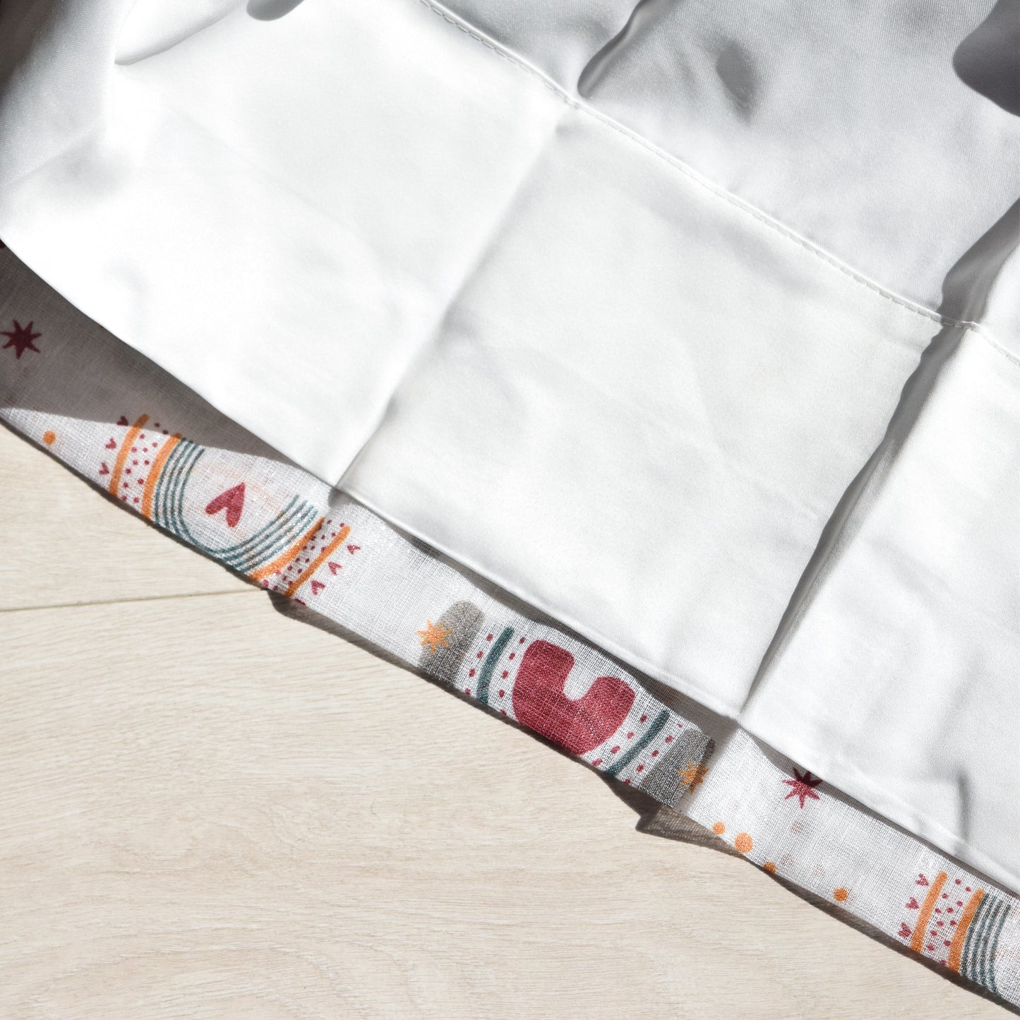 Close-up of a white curtain lining with a patterned trim on a beige background