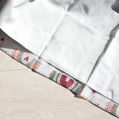 Close-up of a white curtain lining with a patterned trim on a beige background