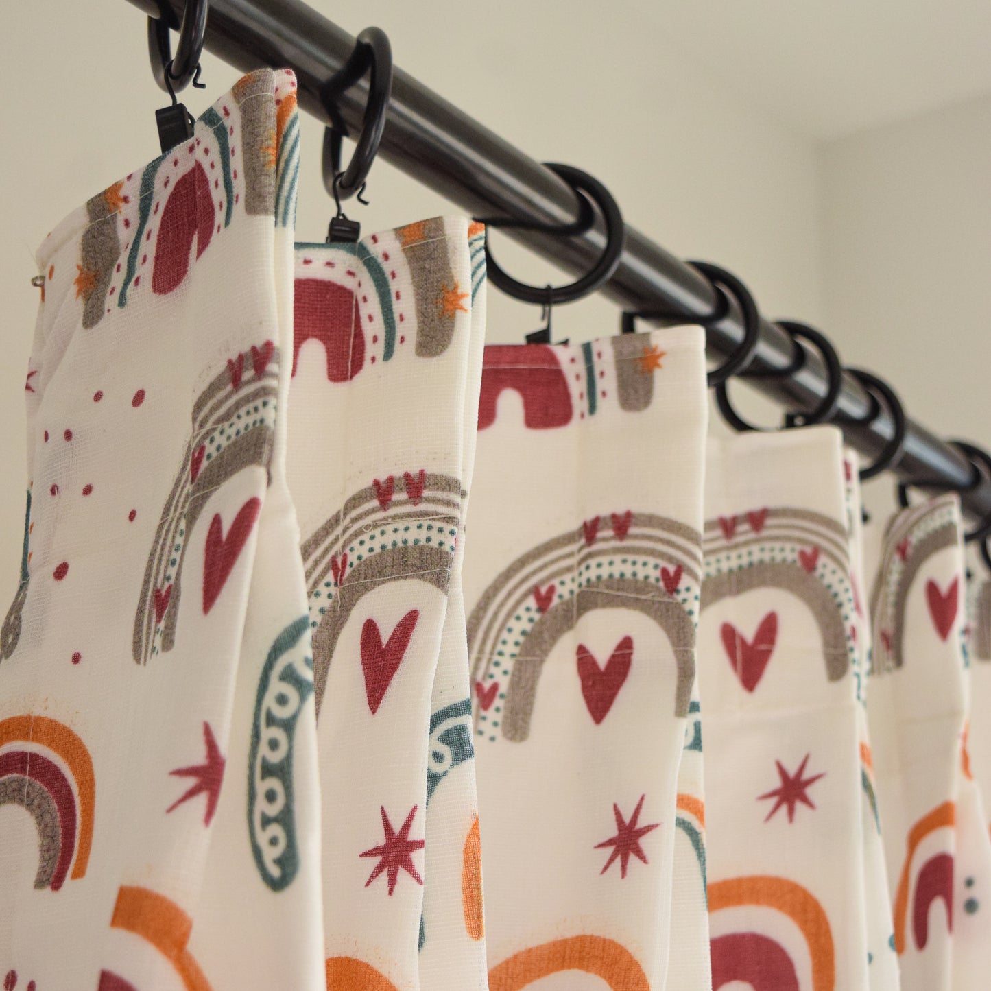 Curtains with rainbow and heart pattern hanging on a rod