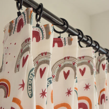 Curtains with rainbow and heart pattern hanging on a rod
