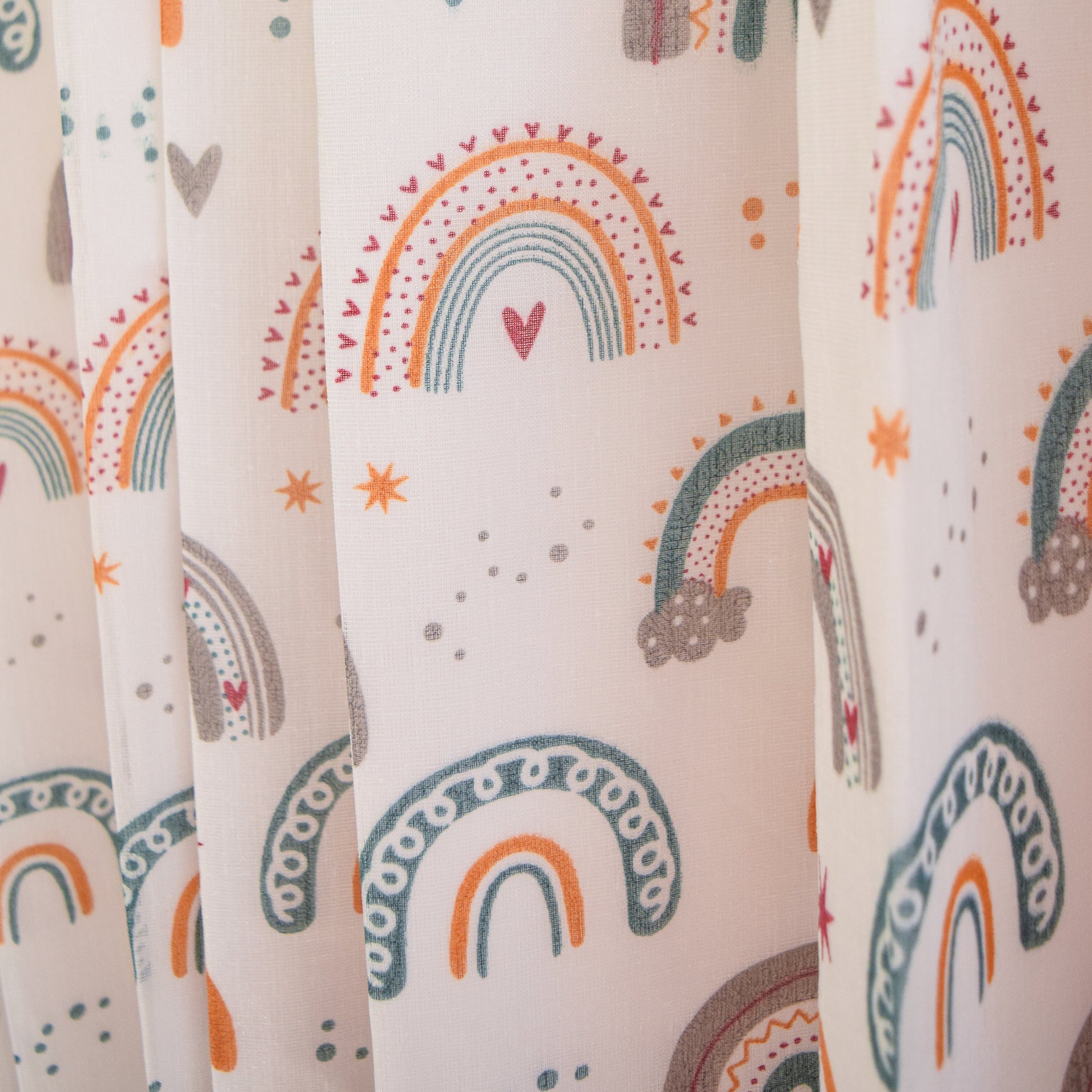 Patterned fabric with colorful rainbows and hearts on a light background