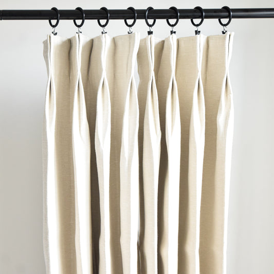 Beige curtains hanging from a rod against a white background