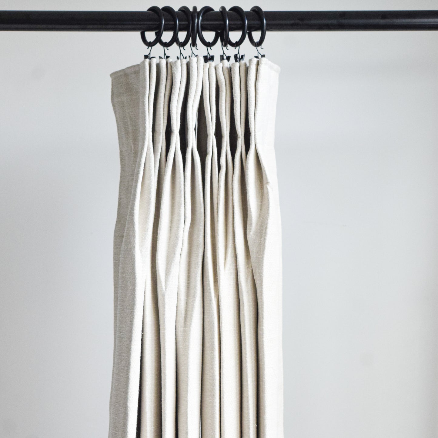 Set of beige curtains hanging on a rod against a white background