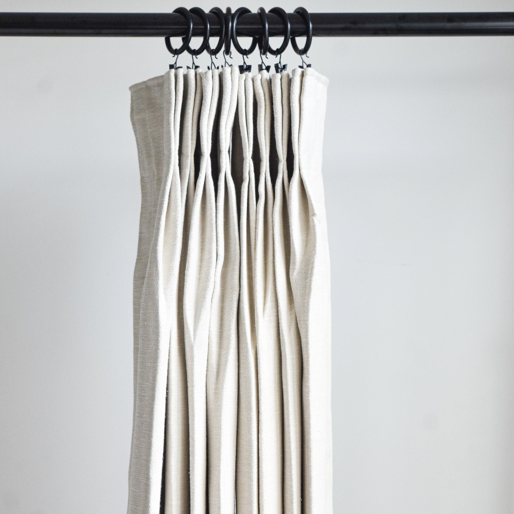 Set of beige curtains hanging on a rod against a white background