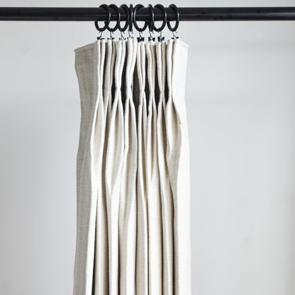 Set of beige curtains hanging on a rod against a white background