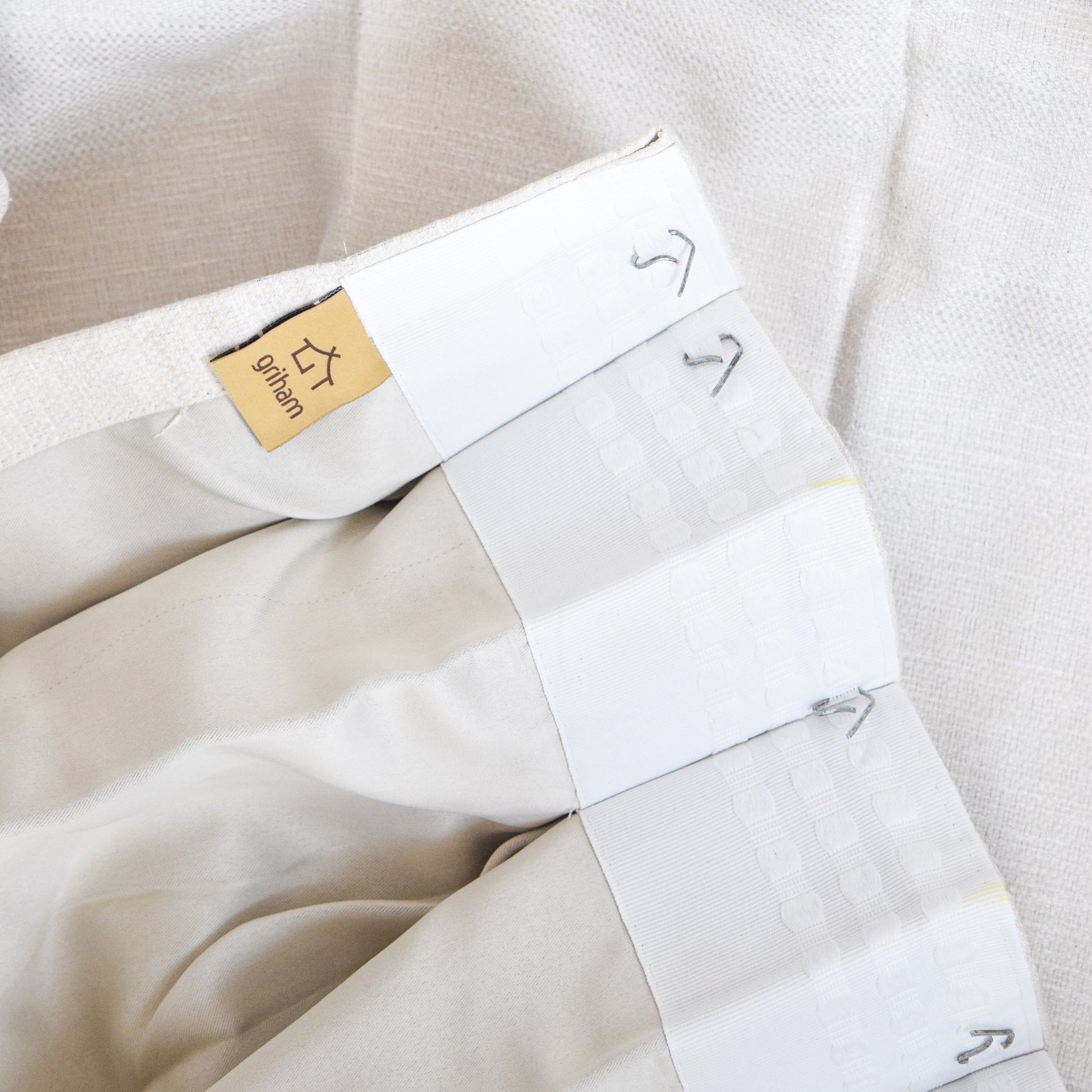 Folded white shirt with a gold label on a light beige background