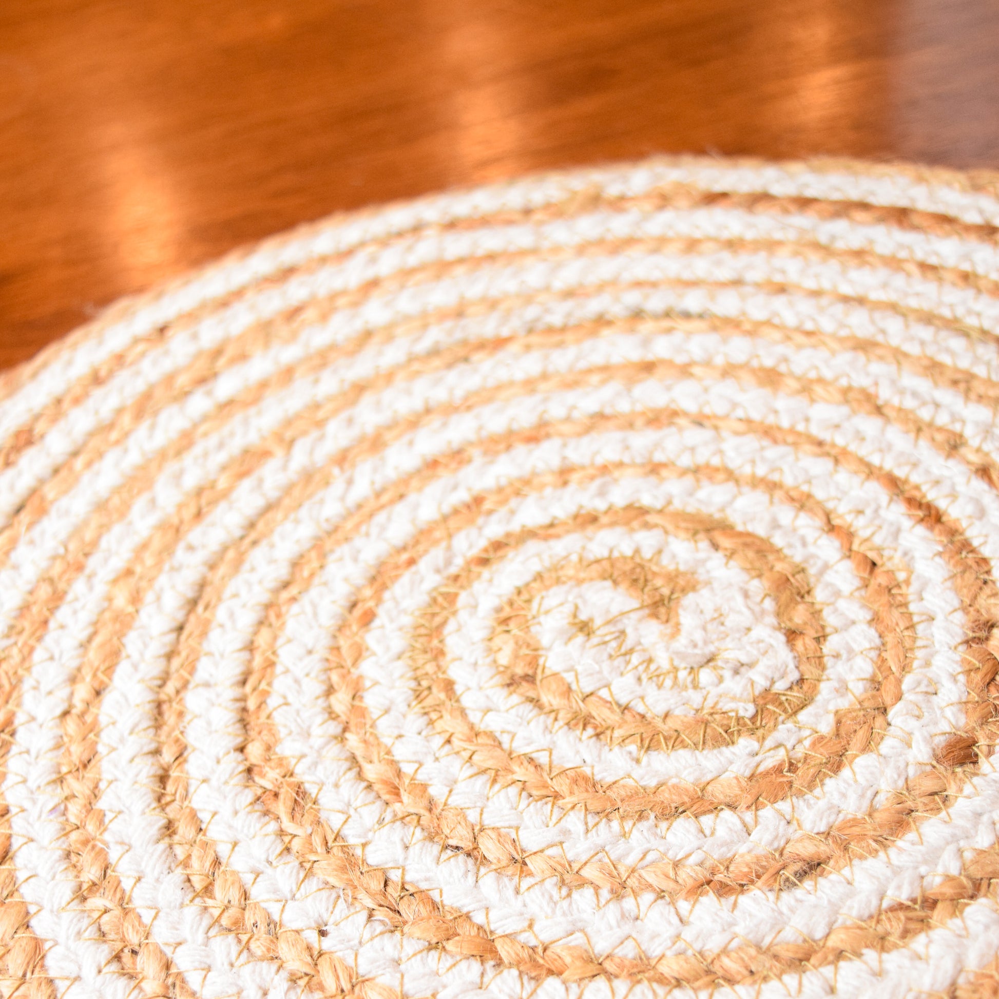 Close-up of a woven circular mat with concentric circles on a wooden surface.