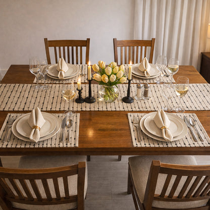 Dining table set with plates, glasses, candles, and a vase of flowers.