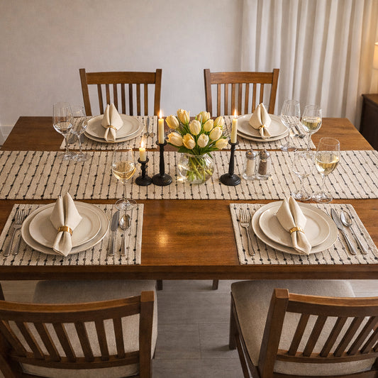 Dining table set with plates, glasses, candles, and a vase of flowers.