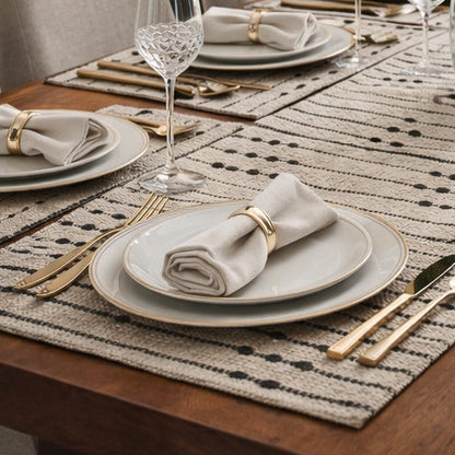 Dining table set with plates, glasses, and a vase of flowers in a well-lit room.
