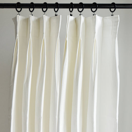 White curtains hanging from a rod against a plain background