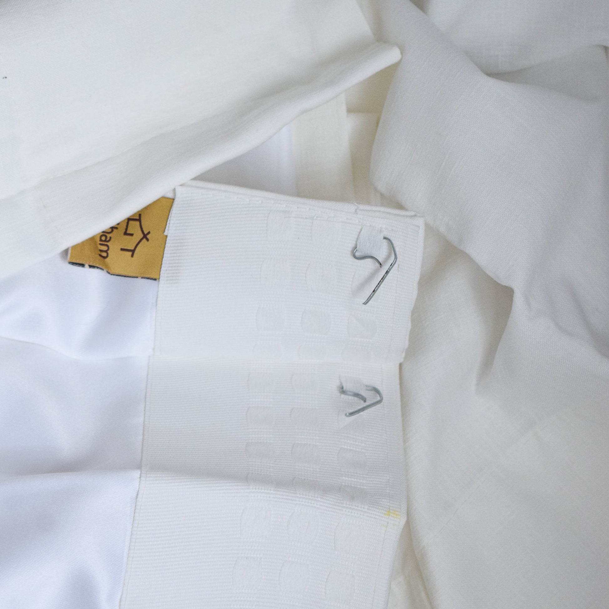 White fabric with embroidered patterns and a wooden tag on a white background